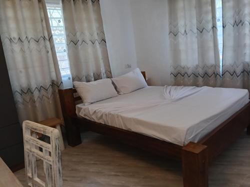 a bedroom with a bed with curtains and a chair at Mobi house Malindi in Malindi