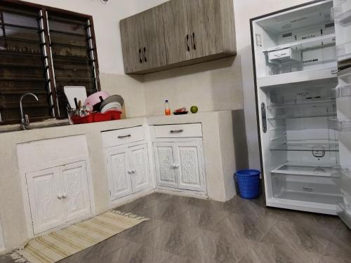 a kitchen with white cabinets and an empty refrigerator at Mobi house Malindi in Malindi