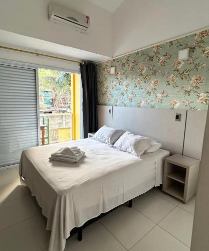 a bedroom with a white bed with a floral wallpaper at Ipê Suites Juquehy in Juquei