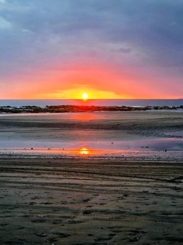 un tramonto su una spiaggia con il sole che tramonta di Casa Poco a Poco a Torio