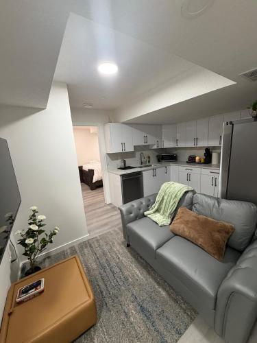 a living room with a couch and a kitchen at Brand New 1 Bedroom Basement Suite in Southwest in Edmonton