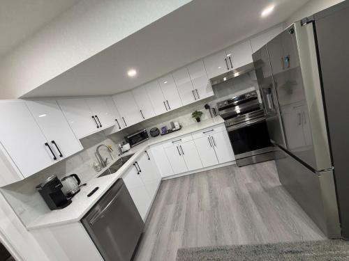a kitchen with white cabinets and stainless steel appliances at Brand New 1 Bedroom Basement Suite in Southwest in Edmonton