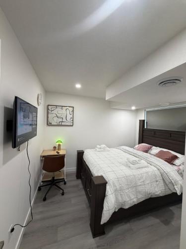 a bedroom with a bed and a television and a table at Brand New 1 Bedroom Basement Suite in Southwest in Edmonton