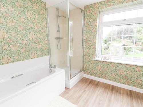 a bathroom with a bath tub and a window at Cae Adar Farm in Wrexham