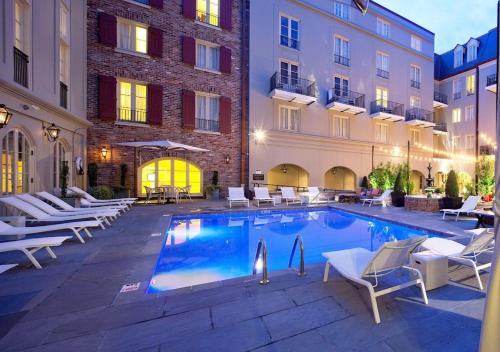a swimming pool in a hotel with chairs and a building at Maison Dupuy Hotel in New Orleans