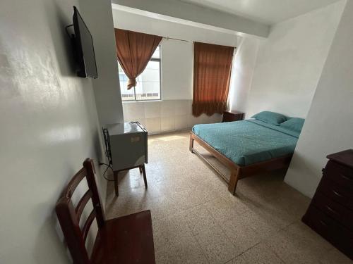 a bedroom with a bed and a table and a window at Hotel luque in Guayaquil