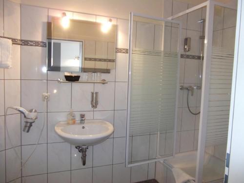 a white bathroom with a sink and a shower at Hotel am Schützenberg in Gotha