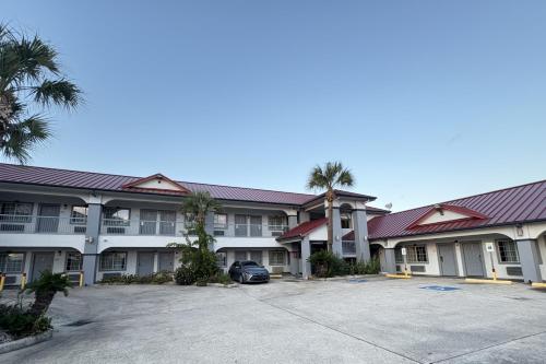 a large apartment building with a parking lot and palm trees at Kiwi Inn Capital O Houston - Hwy 249 in Houston