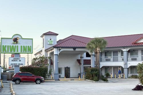 a hotel with a red car parked in a parking lot at Kiwi Inn Capital O Houston - Hwy 249 in Houston