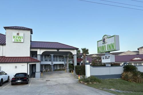 a view of a hotel with a sign and a parking lot at Kiwi Inn Capital O Houston - Hwy 249 in Houston