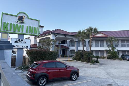 a red car parked in front of a hotel at Kiwi Inn Capital O Houston - Hwy 249 in Houston