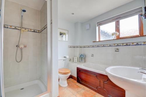a bathroom with a tub and a toilet and a sink at 3 Bed in Holt oc-1331 in Bodham