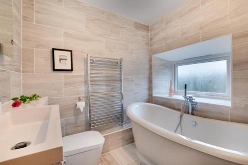 a bathroom with a tub and a toilet and a sink at 5 Bed in Fryup Dale oc-wa291 in Danby