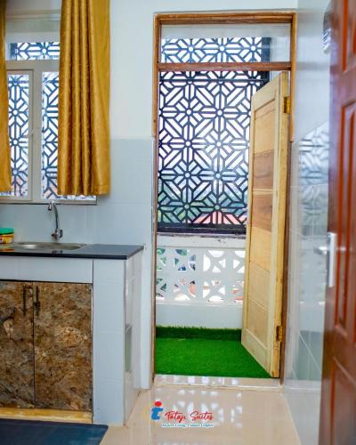 a bathroom with a sink and a door with a window at Tataji Suites in Kisii