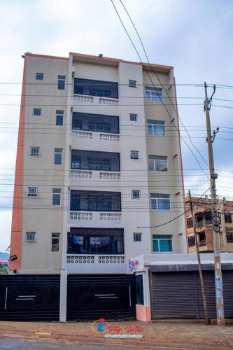 a tall white building with windows and a garage at Tataji Suites in Kisii