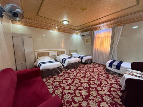 a room with four beds and a red carpet at دار اليقين in Medina