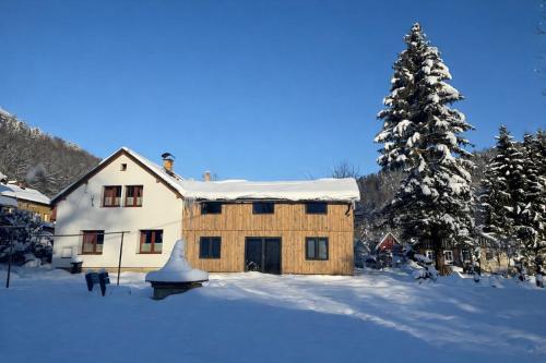 a house in the snow with a snow covered tree at Chata Porcelánka in Desná