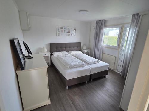 a small bedroom with a bed and a window at Chalet Zon & Zee in Zonnemaire