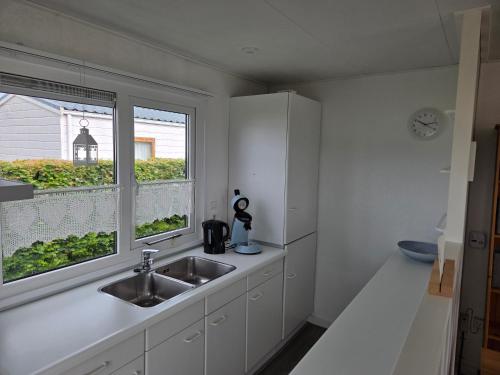 a kitchen with a sink and a window at Chalet Zon & Zee in Zonnemaire