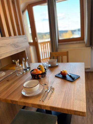 a wooden table with a bowl of fruit on it at Landhotel Bärnriegel in Mauth