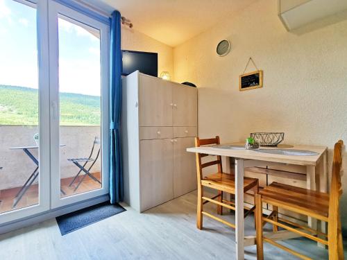 a room with a table and chairs and a sliding glass door at Studio Lélex - classé meublé de tourisme 2 étoiles - pied des pistes - vue montagne in Lélex
