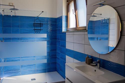 a blue tiled bathroom with a sink and a mirror at Case Vacanze Marinella in Viverone
