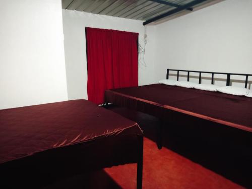two beds in a room with a red curtain at Riverview Adventure Resort in Kitulgala