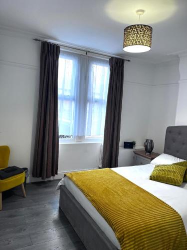 a bedroom with a large bed with a yellow blanket at Feel at Home away from Home in Nottingham