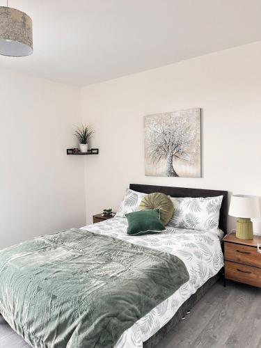 a white bedroom with a bed with a green blanket at Feel at Home away from Home in Nottingham