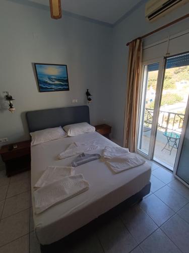 a bedroom with a bed and a sliding glass door at Hotel Asteria in Agios Kirykos