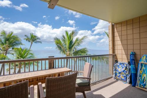 a balcony with chairs and a table and the ocean at Mana Kai 501 in Wailea