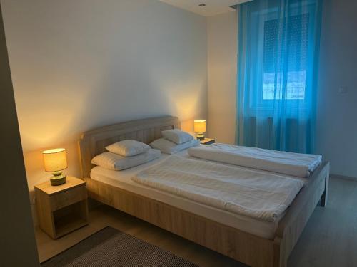 a bedroom with a bed with two lamps and a window at Orchidea Apartmanház Egerszalók in Egerszalók