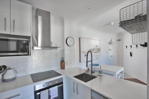 a white kitchen with a sink and a counter at Bila Vista Kirra Beachside Apartments in Gold Coast