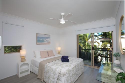 a white bedroom with a bed and a balcony at Bila Vista Kirra Beachside Apartments in Gold Coast