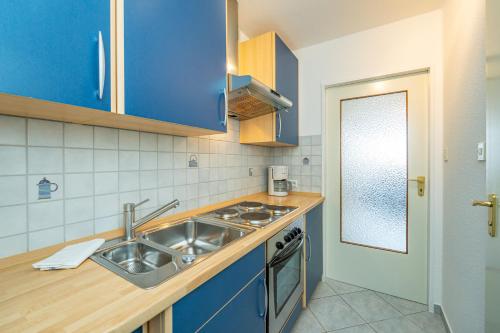 a kitchen with blue cabinets and a sink at Wiking, App 201A in Westerland