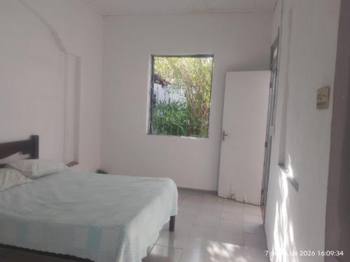 a white bedroom with a bed and a window at Nelson Pinheiro in São Luís