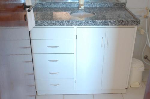a kitchen with white cabinets and a sink at Aqua Villa by Garvetur in Beberibe