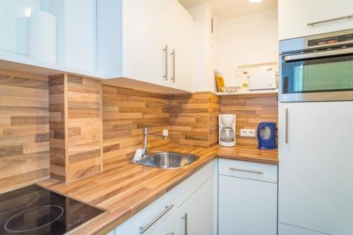 a kitchen with white cabinets and a sink at Sylter Residenz, App 56 in Westerland