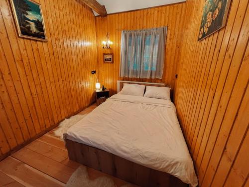 a bedroom with a bed in a wooden wall at Casuta Cerbului Colibita in Colibiţa