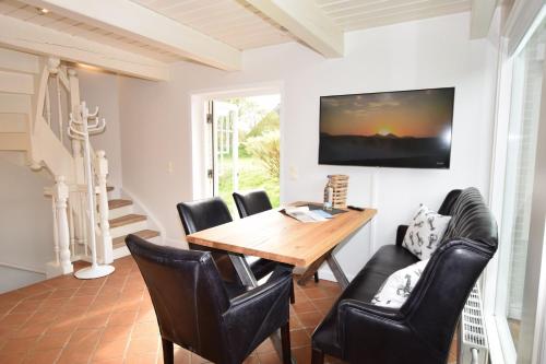 a dining room with a wooden table and leather chairs at Brönswai 5B in Westerland