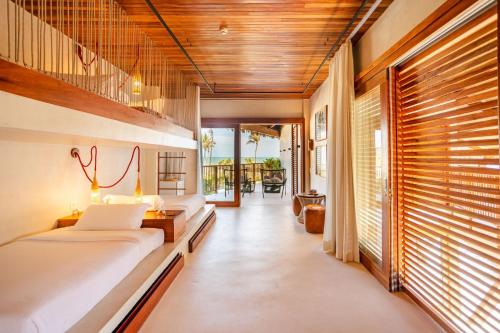 a bedroom with two beds and a hallway with windows at Casa Siará - Hotel & Vilas in Prea