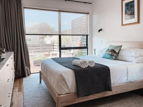 a bedroom with a bed with a large window at Kowhai Cabin - Serene Scandi Escape in Hokitika in Hokitika