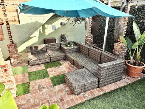 a patio with three wicker couches and an umbrella at Eastside Garden Hideaway For 4 Perfect Location for World Cup Attendees in Long Beach