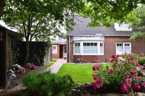 a brick house with a yard with pink flowers at Ferienhaus Litj Stig in Westerland