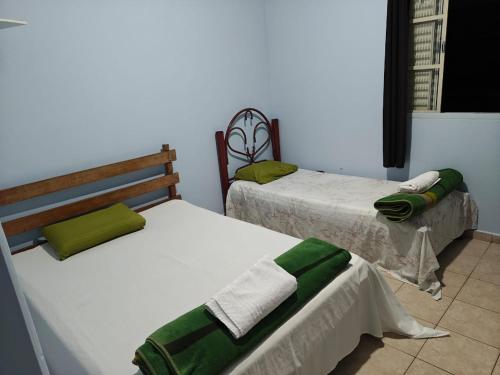 two beds in a room with green and white at Hotel Avenida Paraísopolis MG in Paraisópolis