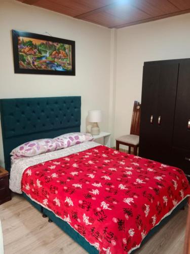 a bedroom with a bed with a red blanket at Habitación familiar Maoservi in Soacha