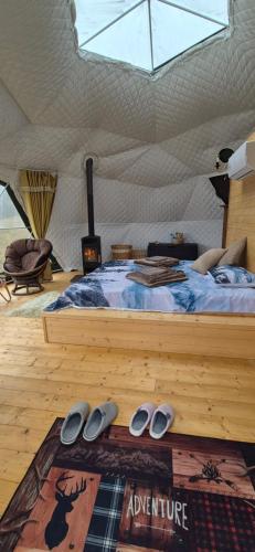 a bed in a tent with a pair of shoes at GLAMPING Považie in Trenčín