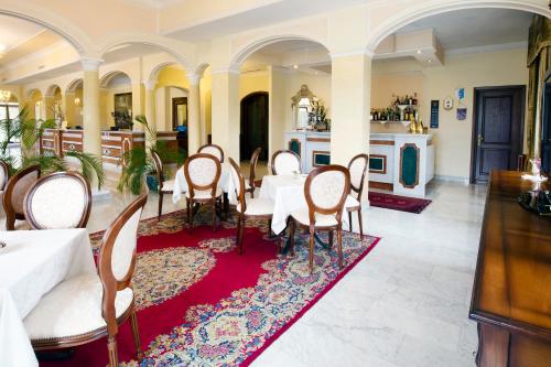 a dining room with a table and chairs on a red rug at Grand Hotel President in Olbia