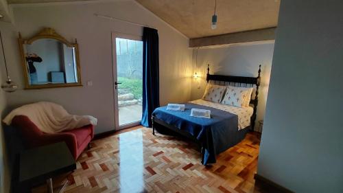 a bedroom with a bed and a chair and a mirror at Casas do Pargo - Casa B Palheiro in Ponta do Pargo