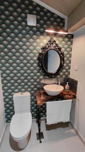 a bathroom with a sink and a toilet and a mirror at Casas do Pargo - Casa B Palheiro in Ponta do Pargo